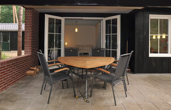 Overdekt terras met grote tafel en terrasheater bij natuurhuisje De Alseïden